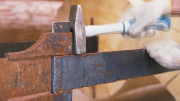 Travailleur portant des gants de protection martelant la construction métallique sur fond de billes de bois. Clip. Travaux de menuiserie sur chantier . — Video