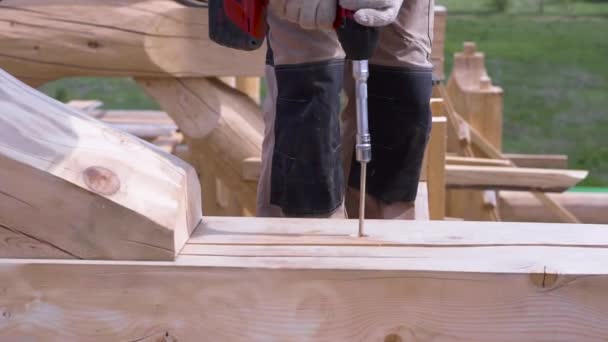 Detailní záběr truhlářských rukou pomocí profesionálního šroubováku venku na staveništi. Klip. Muž pracující s profesionálním vybavením, zatímco dřevěný dům budovy. — Stock video
