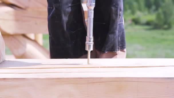 Close up of carpenter hands using professional screwdriver outdoors at construction site. Clip. Man working with professional equipment while wooden house building. — 비디오