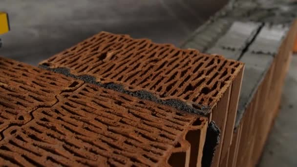 A construction worker removes excess cement from the joint of bricks. Stock footage. Bricklayer laying bricks to make a wall, he is putting grout on top of a brick — 비디오