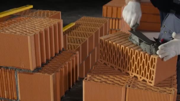 Builder smearing cement on brick block. Stock footage. Close-up of professional Builders hands applying cement to red brick block with spatula — 비디오