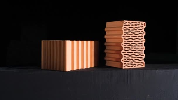 Close-up of two red bricks on black background. Stock footage. Demonstration of two red ceramic blocks with wavy lines for building house on black background — 비디오