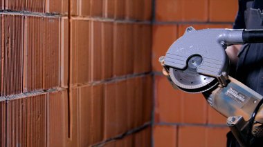 Marangoz öğütücüyle kesiyor. Stok görüntüleri. Profesyonel işçilerin dairesel el testeresiyle tuğla işçiliğini kestiği yakın plan çekimler. Özel inşaat ve marangozluk ekipmanları