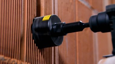 Matkabın başındaki hortum yuvarlak. Stok görüntüleri. Yuvarlak başlıklı profesyonel matkap, kalın tuğla duvarda delik açıyor. Duvardaki matkabın yakın çekimi büyük bir delik açar.