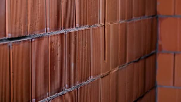 Close-up of background of red brick wall made of blocks. Stock footage. Background of new brickwork of red ceramic blocks. New brickwork with wet cement in crevices — Stock Video