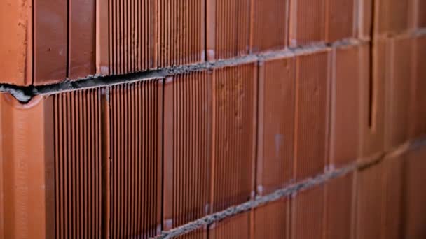 Close-up de fundo de parede de tijolo vermelho feito de blocos. Imagens de stock. Contexto de novos tijolos de blocos de cerâmica vermelha. Nova alvenaria com cimento molhado em fendas — Vídeo de Stock