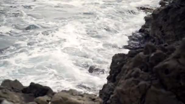 Vlny bojující o skalnaté pobřeží oceánu. Akce. Pohled na zuřící vlny moře lámající se o skály — Stock video