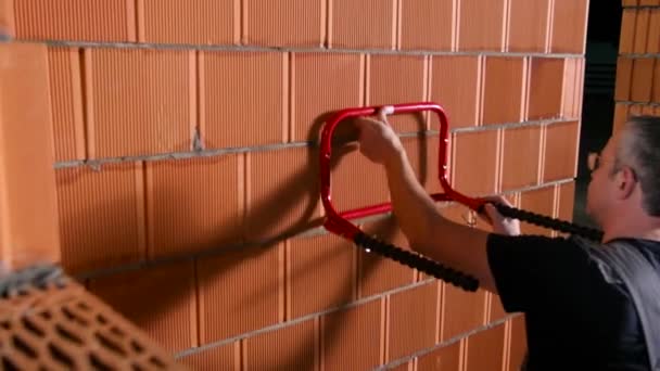 Inicio barra horizontal. Imágenes de archivo. Hombre calificado establece la barra horizontal y hace marca en la pared de ladrillo. Hombre establece bares para los deportes de la familia en casa — Vídeo de stock