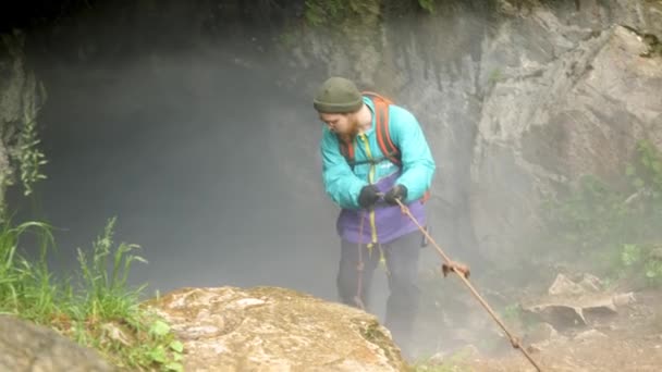 Speleologist descend by the rope in the deep vertical cave tunnel. Stock footage. Man hiker discovering unknown abandoned cave. — Stock Video