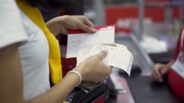 Süpermarketteki kasada mal için para ödeyen bir kadına yakın çekim. Şarjör. Elinde Rus rublesi ve makbuzu olan bir kadın müşteri..