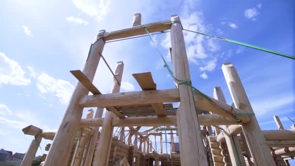 Bauarbeiter bei der Arbeit mit Holzrahmenkonstruktion im Freien an einem Sommertag. Clip. Ansicht des unvollendeten zweistöckigen Gebäudes von unten. — Stockvideo