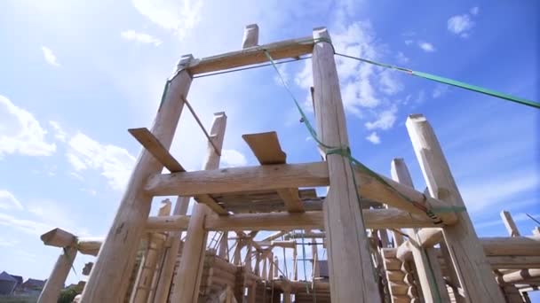 Builder at work with wooden house frame construction outdoors on a summertime. Clip. Bottom view of unfinished two storey building. — Stock Footage Builder at work with wooden house frame construction outdoors on a summertime. Clip. Bottom view of unfinished two storey building. Video Clip
