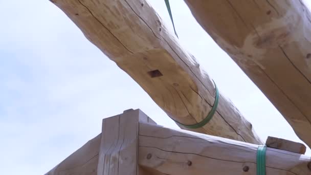 Part of the frame of a wooden house, details of a truss wooden structure, a building made of logs. Clip. Bottom view of lifted round shaped beam. — Stock Footage Part of the frame of a wooden house, details of a truss wooden structure, a building made of logs. Clip. Bottom view of lifted round shaped beam. Video Clip