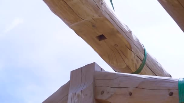 Parte della struttura di una casa in legno, dettagli di una struttura in legno a capriate, un edificio fatto di tronchi. Clip. Vista inferiore del fascio rotondo sollevato . — Video Stock