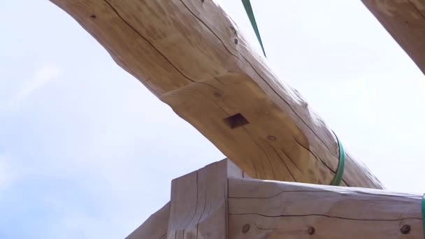 Instalação de vigas de madeira no local de construção, o sistema de treliça do telhado da casa. Clipe. Telhado da casa incompleta no fundo azul céu nublado . — Vídeo de Stock