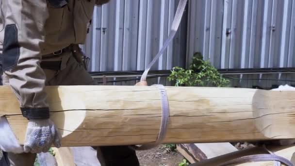 Builder at work with wooden house frame construction outdoors on a summertime. Clip. Carpenter trying to lift the log with the help of a crane. — Stock Footage Builder at work with wooden house frame construction outdoors on a summertime. Clip. Carpenter trying to lift the log with the help of a crane. Royalty Free Stock Footage