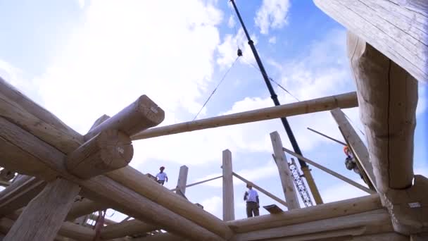 Cadre de la maison en construction, installation des éléments de toit sur fond bleu ciel nuageux. Clip. Travailleurs sur le chantier . — Video