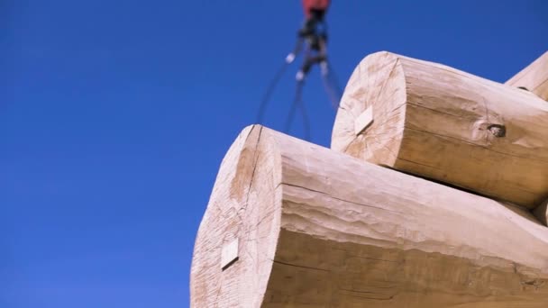 Dettaglio di travi, l'angolo di casa in legno incompiuta su sfondo cielo nuvoloso blu, vista in basso. Clip. Braccio di gru che si muove dietro il telaio in legno . — Video Stock