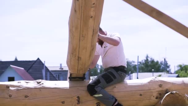 Obrero varón de construcción que construye una casa residencial de dos pisos al aire libre en una hora de verano. Clip. Carpintero en el trabajo con el marco de madera de la casa ecológica . — Vídeos de Stock