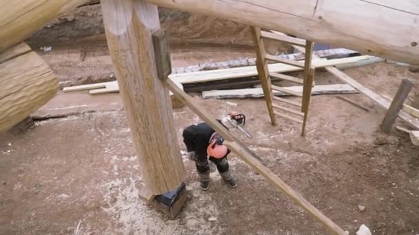 Vista superior de carpintero edificio nueva casa ecológica de madera o casa de campo en la zona rural. Clip. Hombre trabajador con uniforme y casco protector en el sitio de construcción . — Vídeo de stock