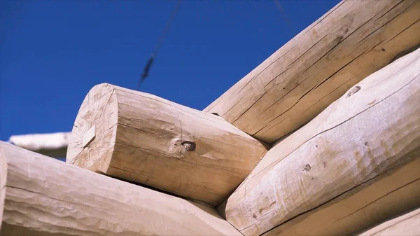 Detail der Balken, die Ecke des unfertigen Holzhauses auf blauem bewölkten Himmel Hintergrund, Ansicht von unten. Clip. Kranausleger bewegt sich hinter dem Holzrahmen. — Stockfoto