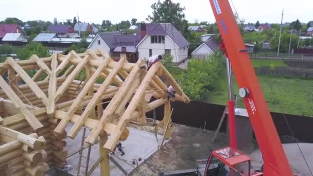 Vista aérea de la zona rural y la construcción de casa de madera, carpintería y concepto de maquinaria. Clip. Proceso de construcción de casas de madera de campo con tripulación y grúa . — Vídeo de stock