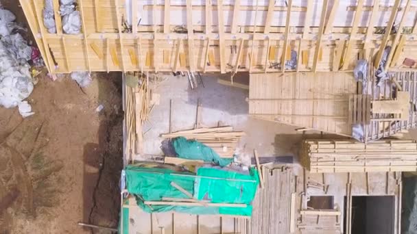 Luchtfoto van de bouwplaats tijdens de bouw van een houten huis van dikke balken van gezaagde bomen. Een knip. Ontbossing en houtverwerkende industrie. — Stockvideo
