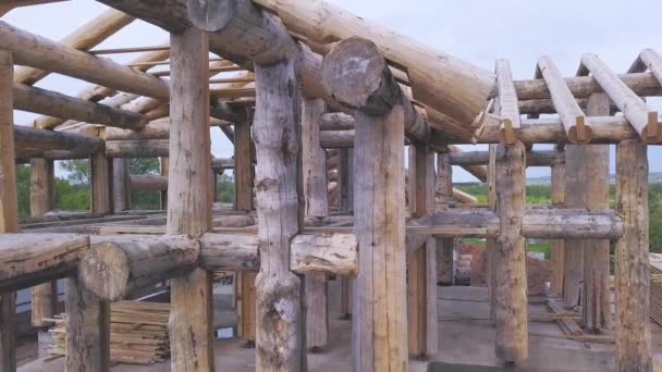 Aerial view of the construction site during the building of a wooden house from thick beams of sawn trees. Clip. Deforestation and woodworking industry concept. — Stock Footage Aerial view of the construction site during the building of a wooden house from thick beams of sawn trees. Clip. Deforestation and woodworking industry concept. Stock Footage