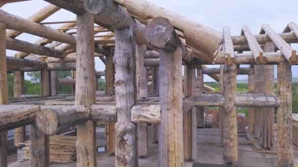 Vista aérea del sitio de construcción durante la construcción de una casa de madera a partir de vigas gruesas de árboles aserrados. Clip. Concepto de la industria de la deforestación y la madera . — Vídeos de Stock