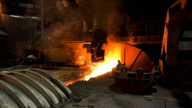 Çelik değirmeninde eriyik demir akıyor ve kenarlarında bir sürü kıvılcım uçuşuyor. Stok görüntüleri. Profesyonel makineli çelik fabrikasının sıcak dükkanı..