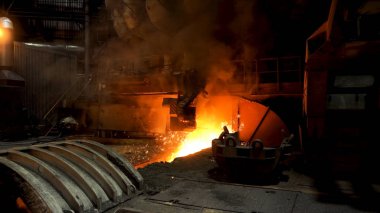 Çelik değirmeninde eriyik demir akıyor ve kenarlarında bir sürü kıvılcım uçuşuyor. Stok görüntüleri. Profesyonel makineli çelik fabrikasının sıcak dükkanı..