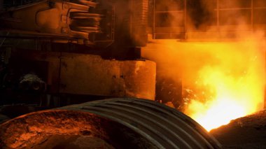 Çelik değirmeninde eriyik demir akıyor ve kenarlarında bir sürü kıvılcım uçuşuyor. Stok görüntüleri. Profesyonel makineli çelik fabrikasının sıcak dükkanı..