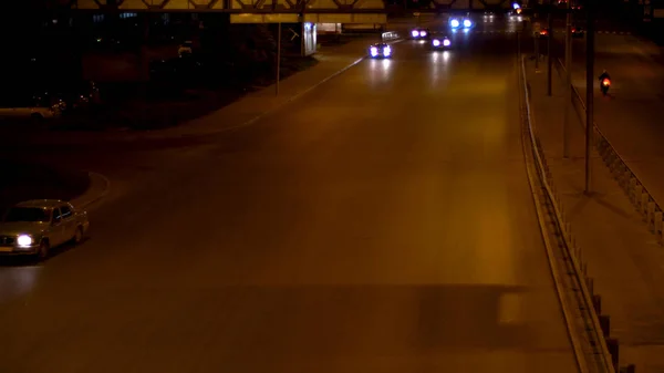 Late evening road lit by the headlights of driving cars. Stock footage. Night traffic in one way street with moving passenger cars. — 스톡 사진