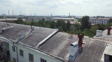 Yeşil yerleşim alanındaki çok katlı apartmanların havadan görüntüsü. Stok görüntüleri. Bulutlu arka planda ağaçlarla çevrili eski evlerin çatılarında uçuyorlar..