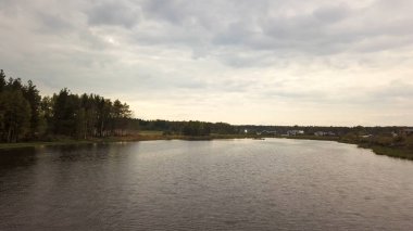 Geniş nehrin yanında yeşil ağaçlar ve bulutlu gökyüzü arka planında çayırlar olan yaz kırsal arazisi, hava manzarası. Stok görüntüleri. Kırsal manzara, yeşil tarlalar ve sakin nehir.