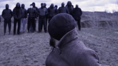 Adam sandalyeye oturup bir grup maskeli suçluya bakıyor. Görüntü. Gangsterlerin buluşma yeri. Opg gruplaması