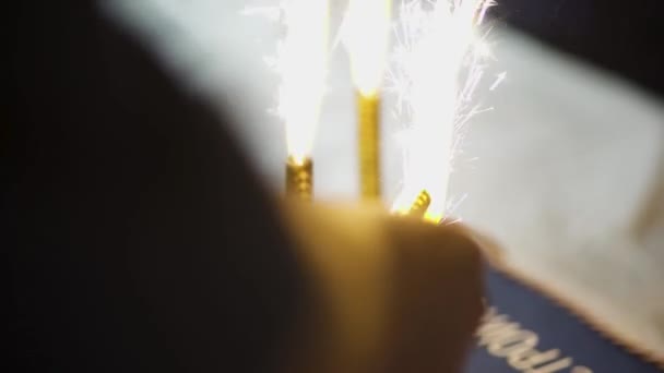 Close-up sparklers are lit. Art. Man lights modern sparklers to celebrate event. Beautiful bright sparklers add solemnity to event — 图库视频影像