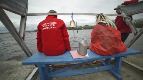 Moscú, Rusia-septiembre de 2019: Salvadores sentados en el muelle. Art. Vista trasera de dos socorristas sentados en el muelle con clima nublado. Dos rescatistas están esperando el final de la carrera de vela de mar — Vídeo de stock