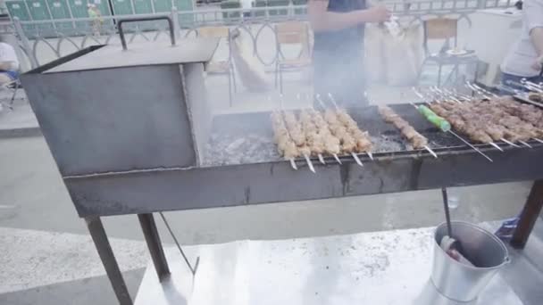 Close-up de kebabs shish preparados na grelha. Arte. Homem profissionalmente prepara kebabs na grelha para venda. Grill está fumando no momento de fritar kebabs suculentos — Vídeo de Stock