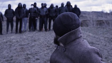 Adam sandalyeye oturup bir grup maskeli suçluya bakıyor. Görüntü. Gangsterlerin buluşma yeri. Opg gruplaması