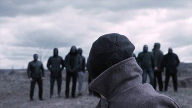 Adam sandalyeye oturup bir grup maskeli suçluya bakıyor. Görüntü. Gangsterlerin buluşma yeri. Opg gruplaması