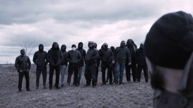 Adam sandalyeye oturup bir grup maskeli suçluya bakıyor. Görüntü. Gangsterlerin buluşma yeri. Opg gruplaması