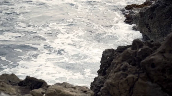De golven die vechten om de rotsachtige oceaankust. Actie. Zicht op de woedende golven van de zee die breken op de rotsen — Stockfoto