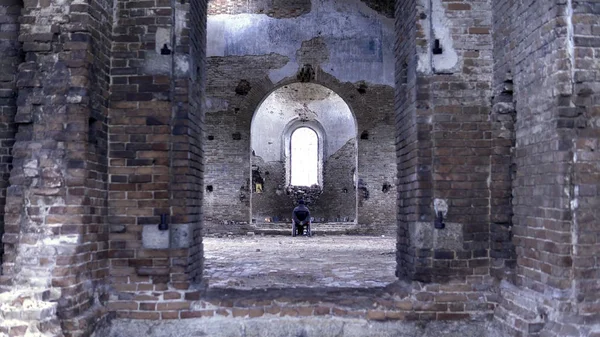 Un hombre en silla de ruedas en una iglesia arruinada. Filmación. Vista posterior de un hombre en una iglesia abandonada. El concepto de recuerdos —  Fotos de Stock