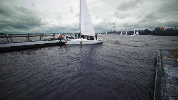 Moscow, Russia-September 2019: Yacht with people sailed to pier on background of cloudy sky. Art. Sea travel and active recreation on yacht in cloudy weather. Sea sports recreation on sailing yacht — Stock Photo, Image