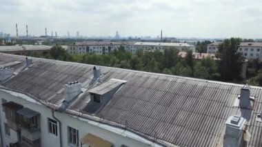 Yeşil yerleşim alanındaki çok katlı apartmanların havadan görüntüsü. Stok görüntüleri. Bulutlu arka planda ağaçlarla çevrili eski evlerin çatılarında uçuyorlar..