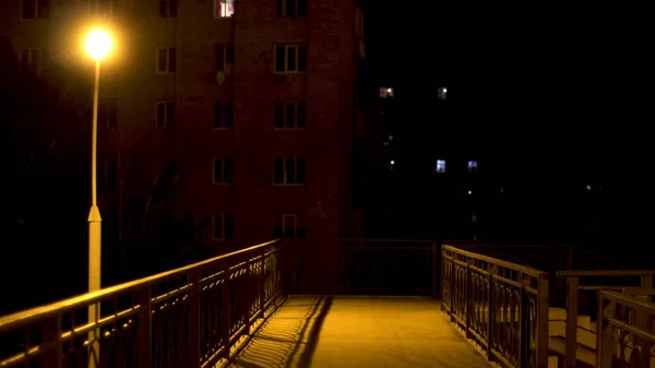 Lighted empty pedestrian bridge lit by the only street lamp. Stock footage. Empty pedestrian bridge over road with no people at nigh time with street light on. — 스톡 사진