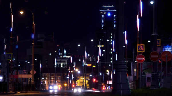 La calle de la ciudad de noche Ekaterimburgo, las luces brillantes de los edificios y el rascacielos Visotsky. Imágenes de archivo. Muchos coches que conducen por la noche . — Foto de Stock