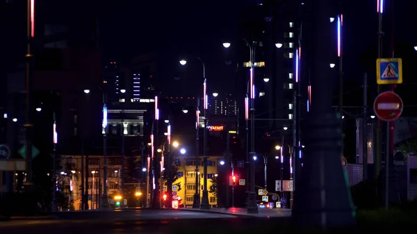 Paisagem noturna do grande centro da cidade com luzes brilhantes e carros raros em movimento. Imagens de stock. Estrada da zona central da cidade iluminada por lâmpadas de rua . — Fotografia de Stock