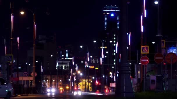 Night landscape of the big city center with shining lights and moving rare cars. Stock footage. Road of the central city district lit by street lamps. — Stock Video